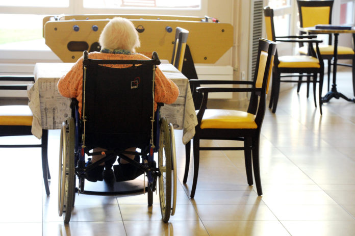 Personne âgée dans un fauteuil roulant dans une maison de retraite ; @Tesson/andia