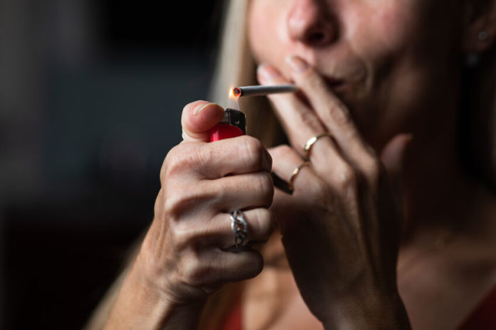 Une femme allumant une cigarette 123RF©