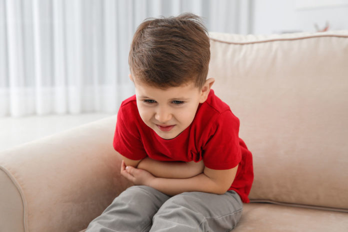 Petit garçon ayant mal au ventre assis sur un canapé