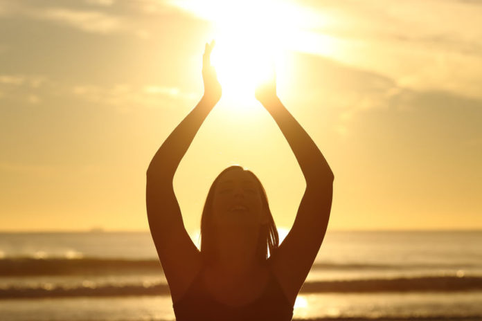 Femme faisant la salutation au soleil