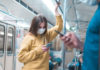 Jeune femme avec masque dans le métro regardant son smartphone
