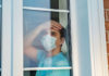 Un homme avec un masque regarde par la fenêtre