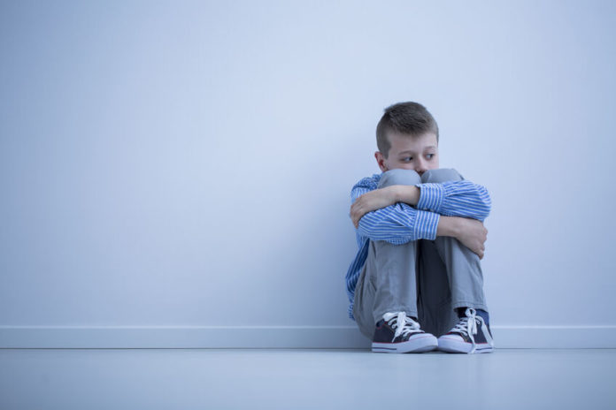Jeune garçon assis contre un mur