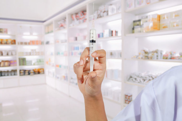 Main d'un pharmacien s'apprêtant à injecter un vaccin en officine